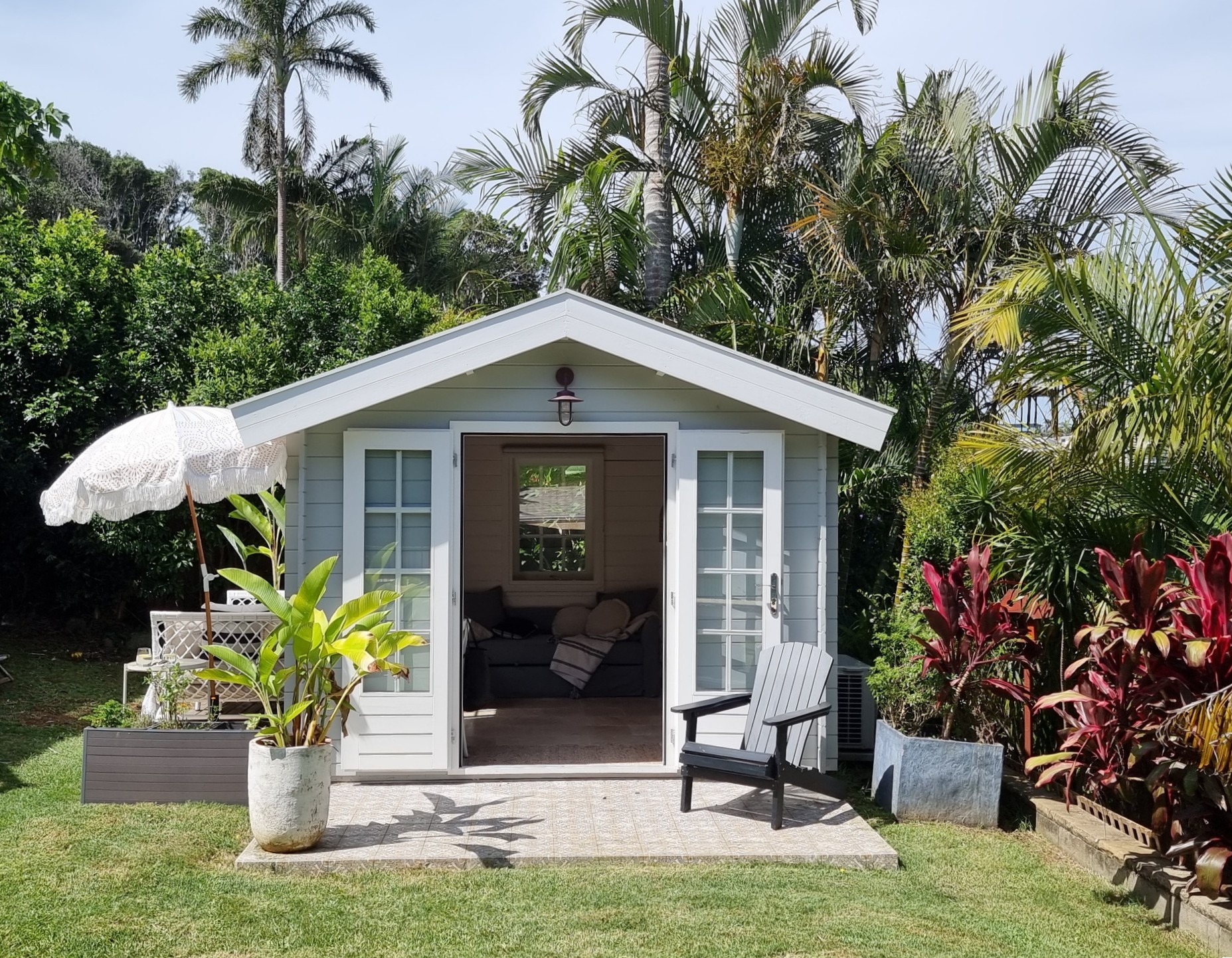 outside of painted cabana cabin backyard retreat with side deck and open french doors tropical