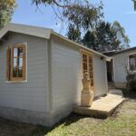 outside of woodland cabin used as backyard retreat with casement window and french doors and custom stone path