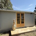 outside of woodland cabin used as backyard retreat with french doors and custom stone path