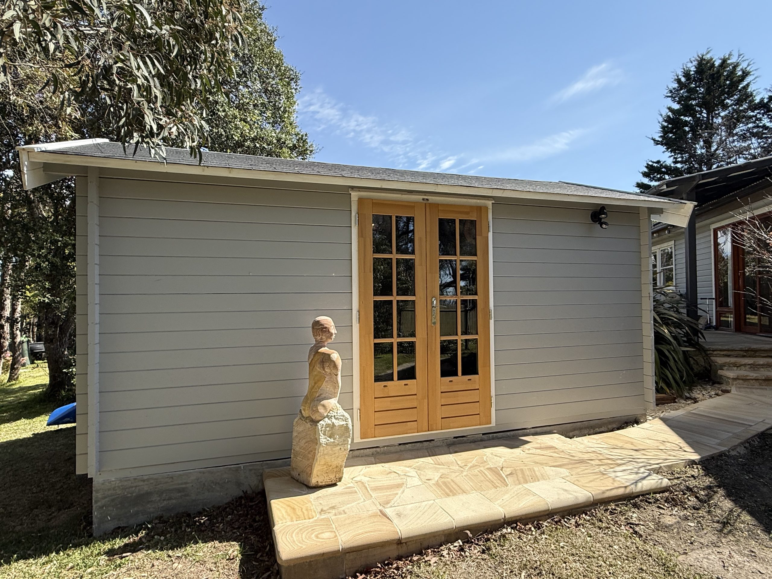 outside of woodland cabin used as backyard retreat with french doors and custom stone path