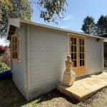 outside of woodland cabin used as backyard retreat with casement window and french doors and custom stone path