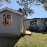 outside of woodland cabin used as backyard retreat with casement window and french doors and custom stone path