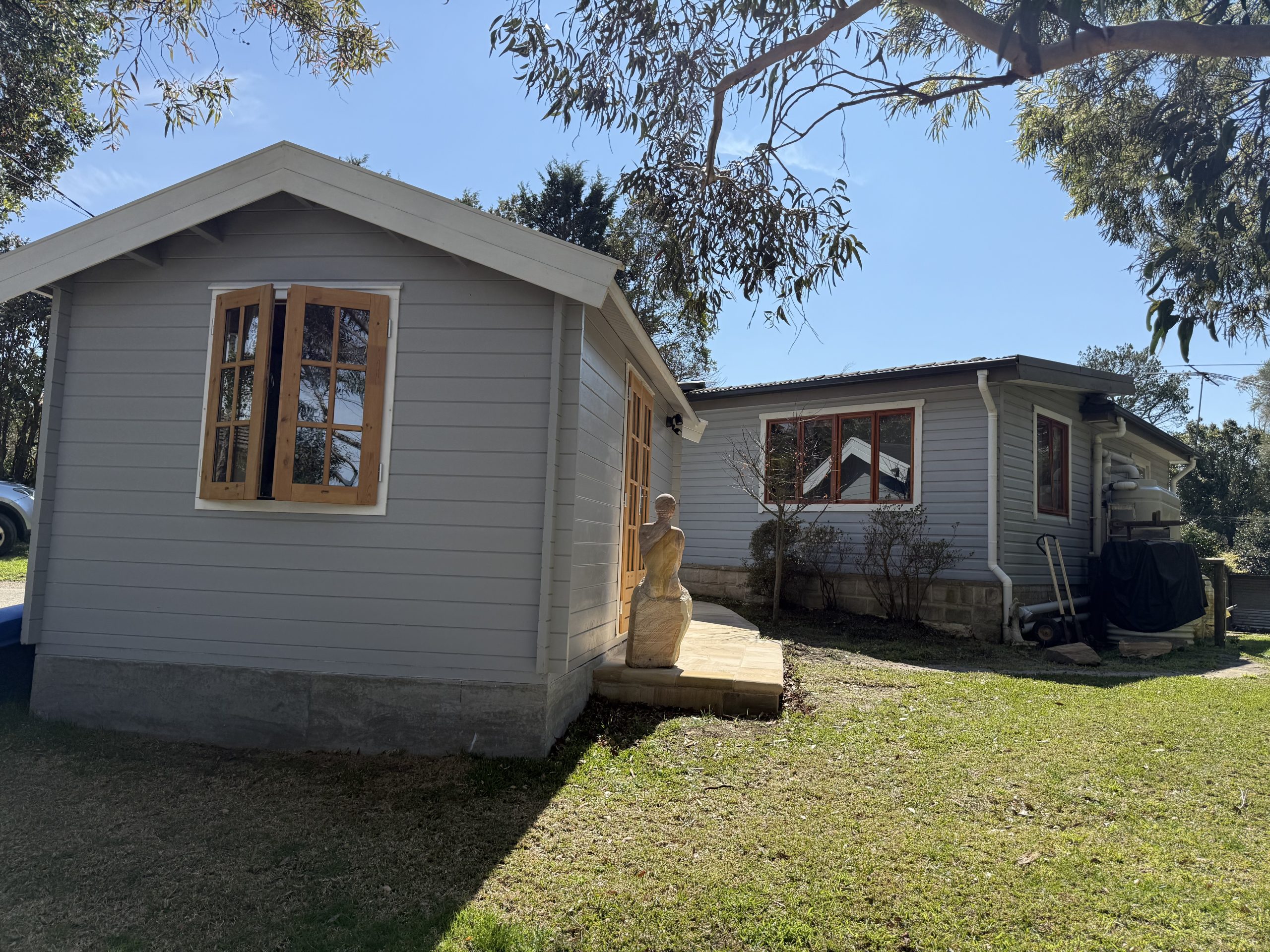 outside of woodland cabin used as backyard retreat with casement window and french doors and custom stone path
