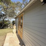 outside of woodland cabin used as backyard retreat with french doors and custom stone path