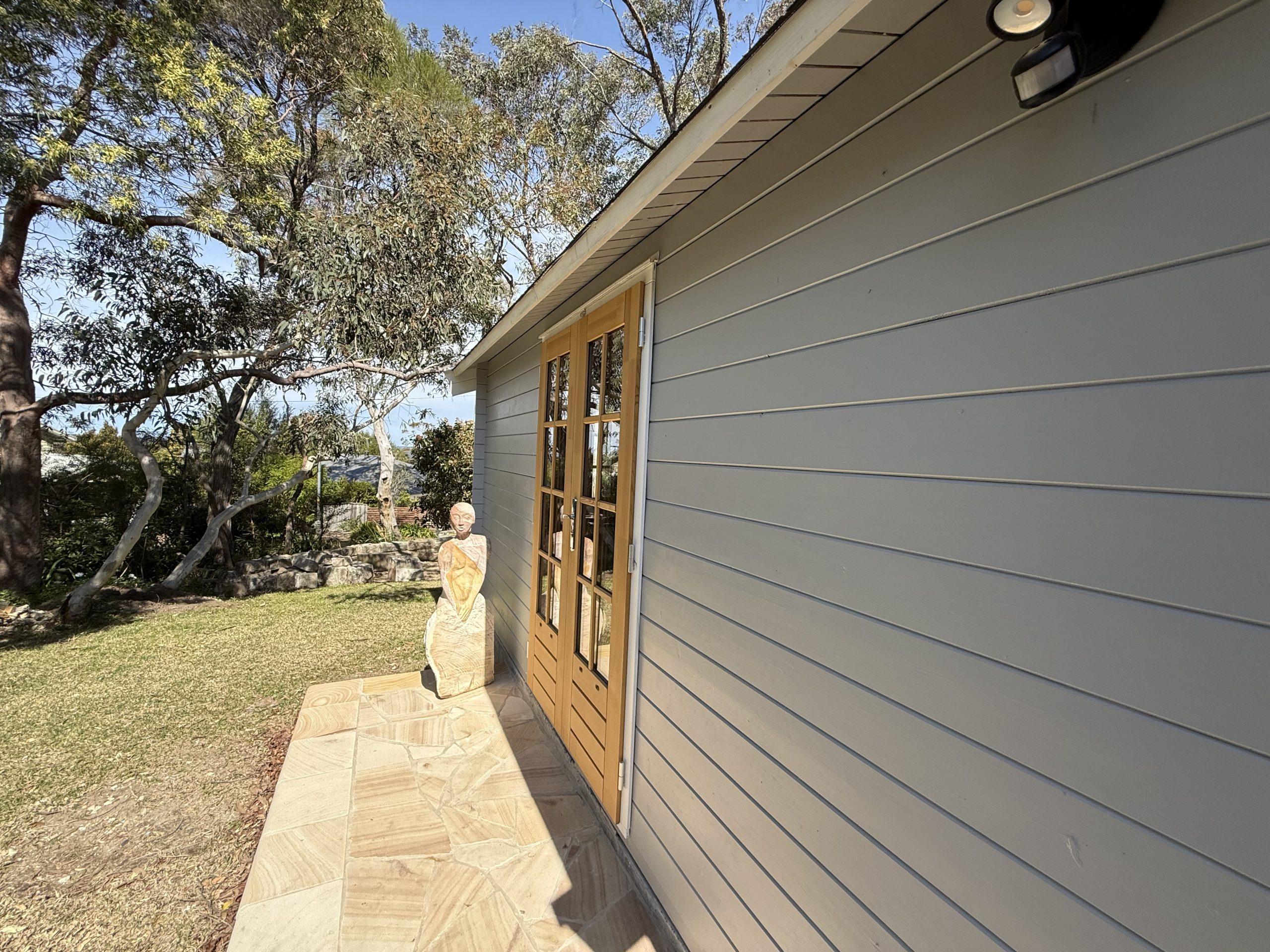 outside of woodland cabin used as backyard retreat with french doors and custom stone path