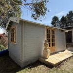 outside of woodland cabin used as backyard retreat with casement window and french doors and custom stone path