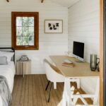 looking into white painted star canopy cabin with a casement window with a bed and desk