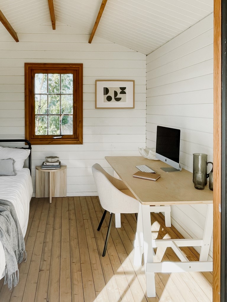 looking into white painted star canopy cabin with a casement window with a bed and desk