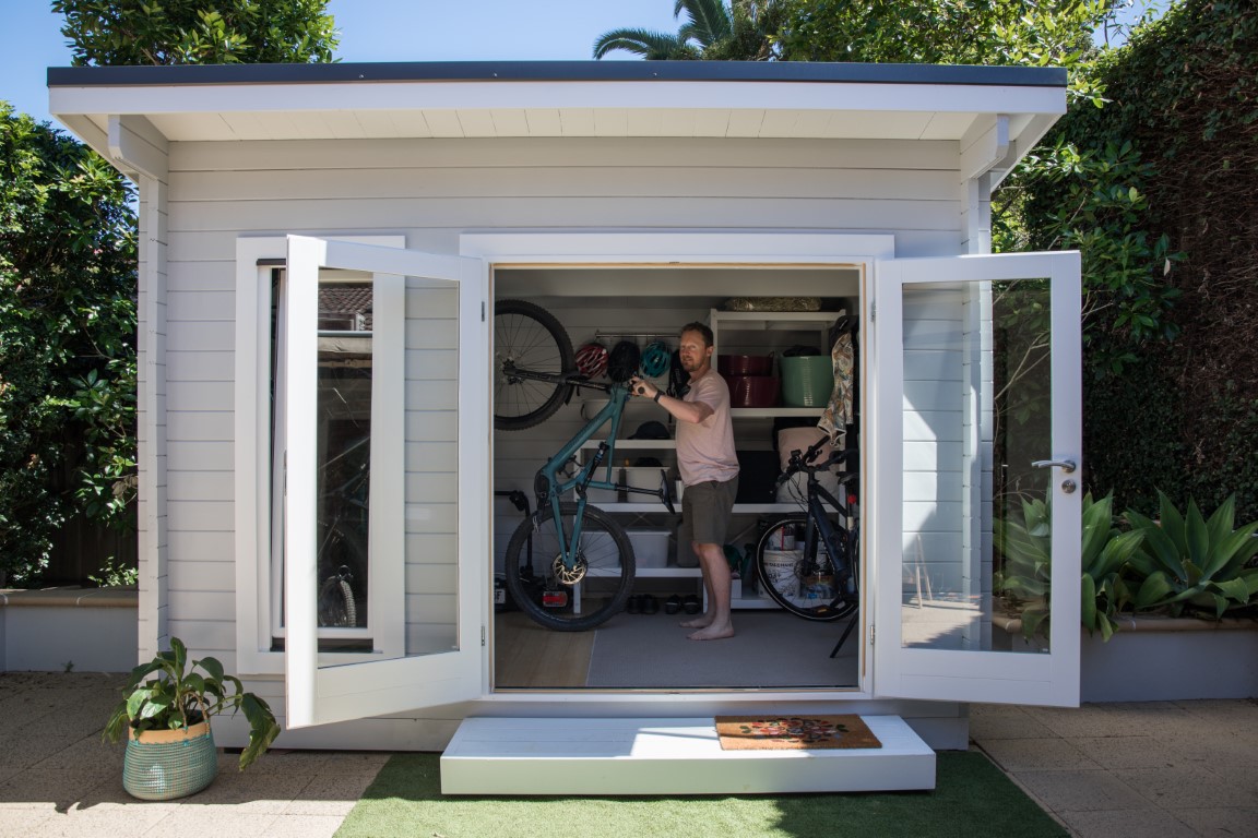 outside of painted tussock cabin bike storage with open door
